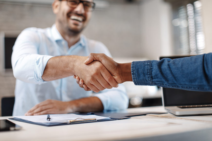 Zwei glückliche Menschen in Business Outfits schütteln sich die Hände