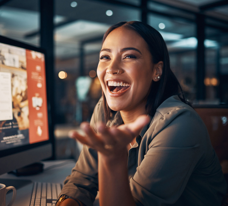 Frau arbeitet lachend am Computer
